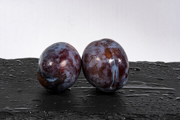 dos ciruelas sobre un plato de pizarra negro