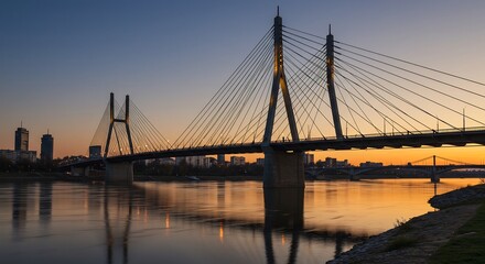 Obraz premium 夕焼け空に映える壮大な吊り橋、水面に美しいシルエットを描き出す。