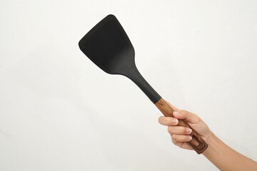 female hand holding black spatula isolated on white background