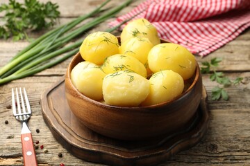 Tasty young boiled potatoes with dill served on wooden table, closeup
