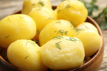 Tasty young boiled potatoes with dill on wooden table, closeup
