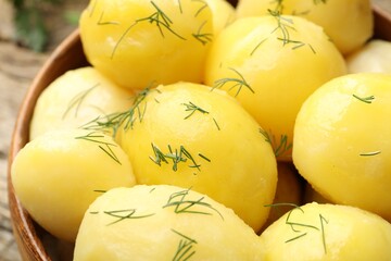 Tasty young boiled potatoes with dill on wooden table, closeup
