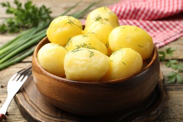 Tasty young boiled potatoes with dill served on wooden table, closeup