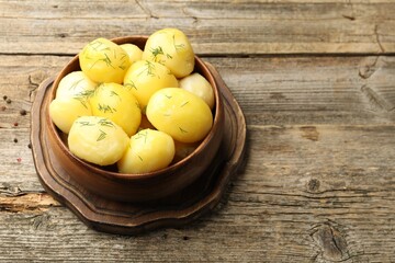 Tasty young boiled potatoes with dill served on wooden table, closeup. Space for text
