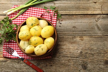 Tasty young boiled potatoes with dill served on wooden table, flat lay. Space for text