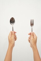 Female hands isolated showing two hands holding spoon and fork on white background, gesture of...