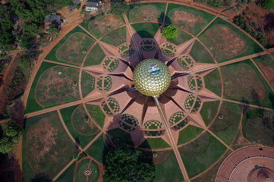 Aerial view of the golden globe-like structure of Matrimandir with its radiating petals surrounded by lush green gardens, Bommayapalayam, Tamil Nadu, India.