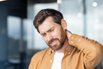 Businessman suffering neck pain at office: stress and muscle tension
