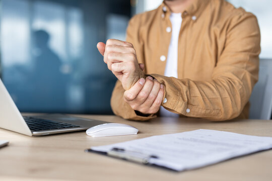 Office worker experiencing wrist pain while working on laptop