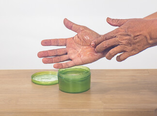 Senior man apply aloe vera gel on skin peeling hand.