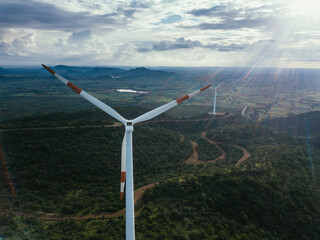 Aerial view of towering wind turbines stand as sentinels amidst the undulating green hills, their blades catching the sun's rays, Hosur, Karnataka, India.