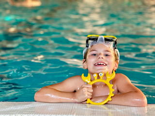 Happy little girl with in swimming pool learning to dive. Little school child with swimm glasses,...