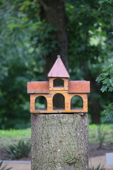 Wooden birdhouse shaped like small castle on tree trunk