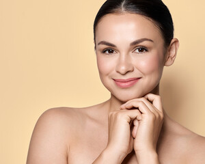 Beauty woman with fresh, moisturized facial skin and natural plump lips over beige or pastel...