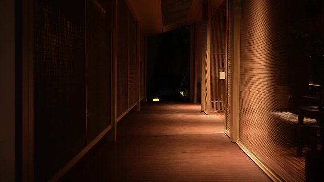 Dimly lit corridor with warm lighting extending into a quiet indoor passageway