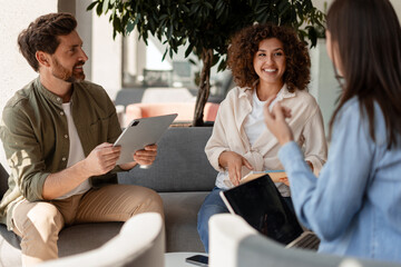 Coworkers having informal meeting using digital tablet and laptop