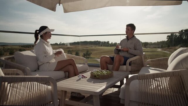 Successful young couple rests drinking coffee after golf training