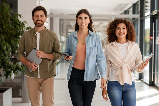 Business people walking through office corridor holding digital tablet and smartphone