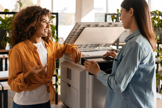 Two businesswomen using printer in modern office