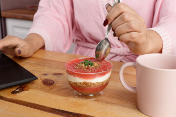 woman in bathrobe after a shower eats delicious dessert for breakfast in the home office.