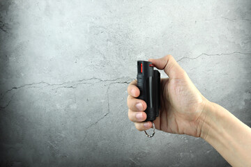 pepper spray or oleoresin capsicum canister with red trigger, also known as OC spray is in right...
