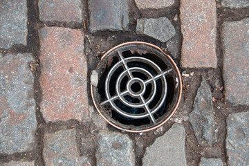 A arial view of a drain cover inbatween a bricked path