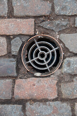 A arial view of a drain cover inbatween a bricked path