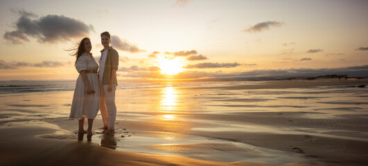 Couple enjoying romantic sunset on sandy beach