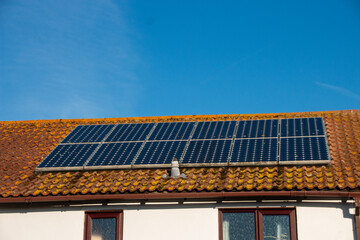 A view of solar panels on a roof top on a beautiful, bright, summers day.