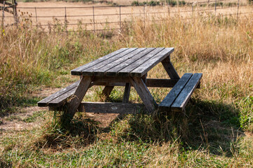 A view of a wooden bench in the middle oif a grass field