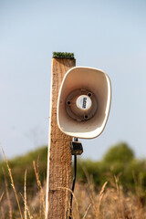 A view of a speaker on a pole in a open grass public area