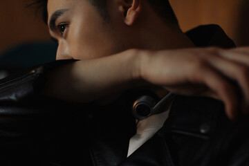 Stylish man in a leather jacket looking pensive indoors.