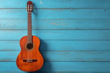 Obraz premium A brown acoustic guitar rests against a light blue wooden plank wall