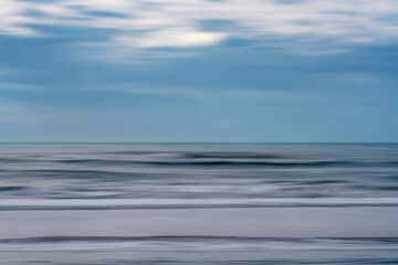 Abstract seascape with blurred waves and soft, streaked clouds in a tranquil palette.