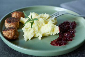 Mashed potatoes with cranberry sauce on a green plate, closeup