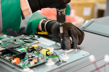 Worker assembling electronic components in a television manufacturing plant during daytime operations