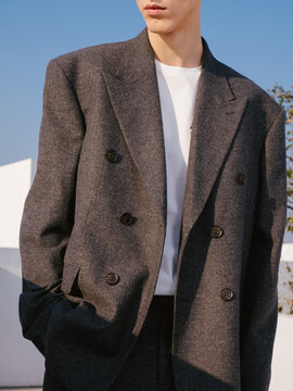 Stylish young man in gray double-breasted blazer standing outdoors.