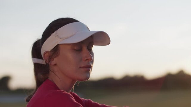Woman in visor hat looks forward standing on golf field