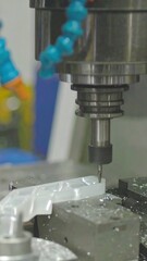 A metallic machining center precisely cuts a translucent white plastic part, showcasing intricate detail and industrial precision.