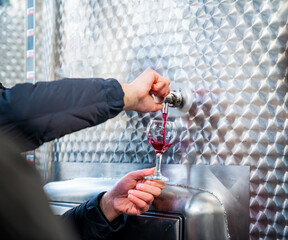 Red wine being poured from a fermenting tank for tasting