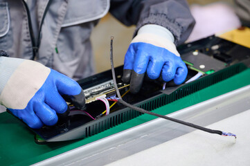 Workers assemble PCB into plastic housing for electronics manufacturing in a factory