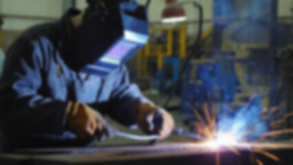 blurry image of someone welding iron, there are sparks, the person is wearing safety clothing, blurry wallpaper
