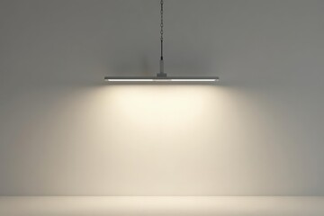 Illuminated interior space showcasing a minimalist pendant light fixture with a sleek, linear design element hanging from a simple chain against a neutral backdrop.