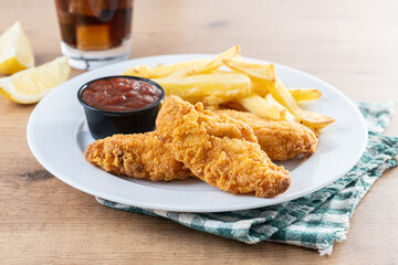 Crispy fried chicken tenders with french fries on wooden table