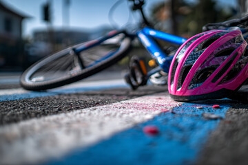 Accident scene with a bicycle and a helmet lying on the ground after a crash on a street crossing.