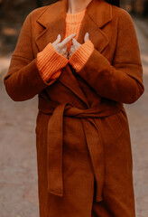 Fashion details of classy brown coat and orange knitting sweater, autumnal fashion cloth concept
