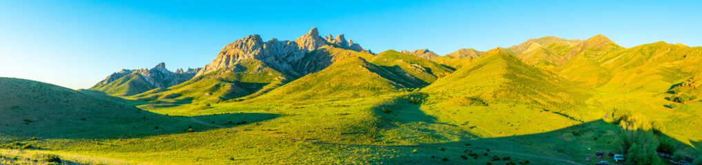 Sunset over green hills and valley, illuminated by the golden sunlight.
