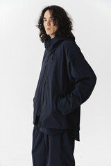 Man in navy jacket with curly hair standing confidently indoors.