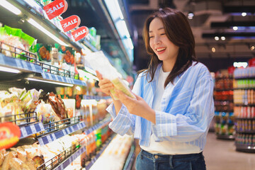 Asian woman shopping in supermarket, smiling and choosing healthy groceries ,Lifestyle concept of consumer behavior in modern retail market