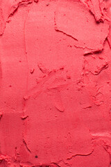 Overhead view of red lipstick, red cream blush and red cosmetic spread on a white background, red cream texture spread on a white countertop